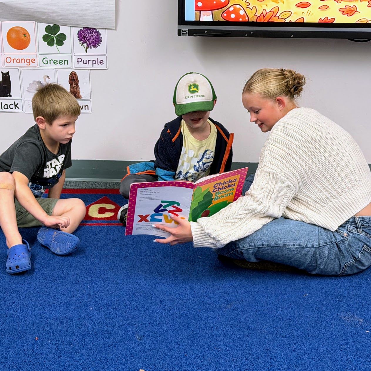 A high school student reads to two kindergarteners